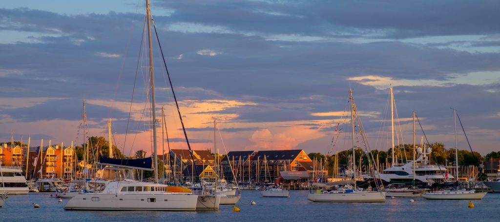 View of Annapolis, Maryland waterfront with multiple sailboats on the water overlooking townhomes.